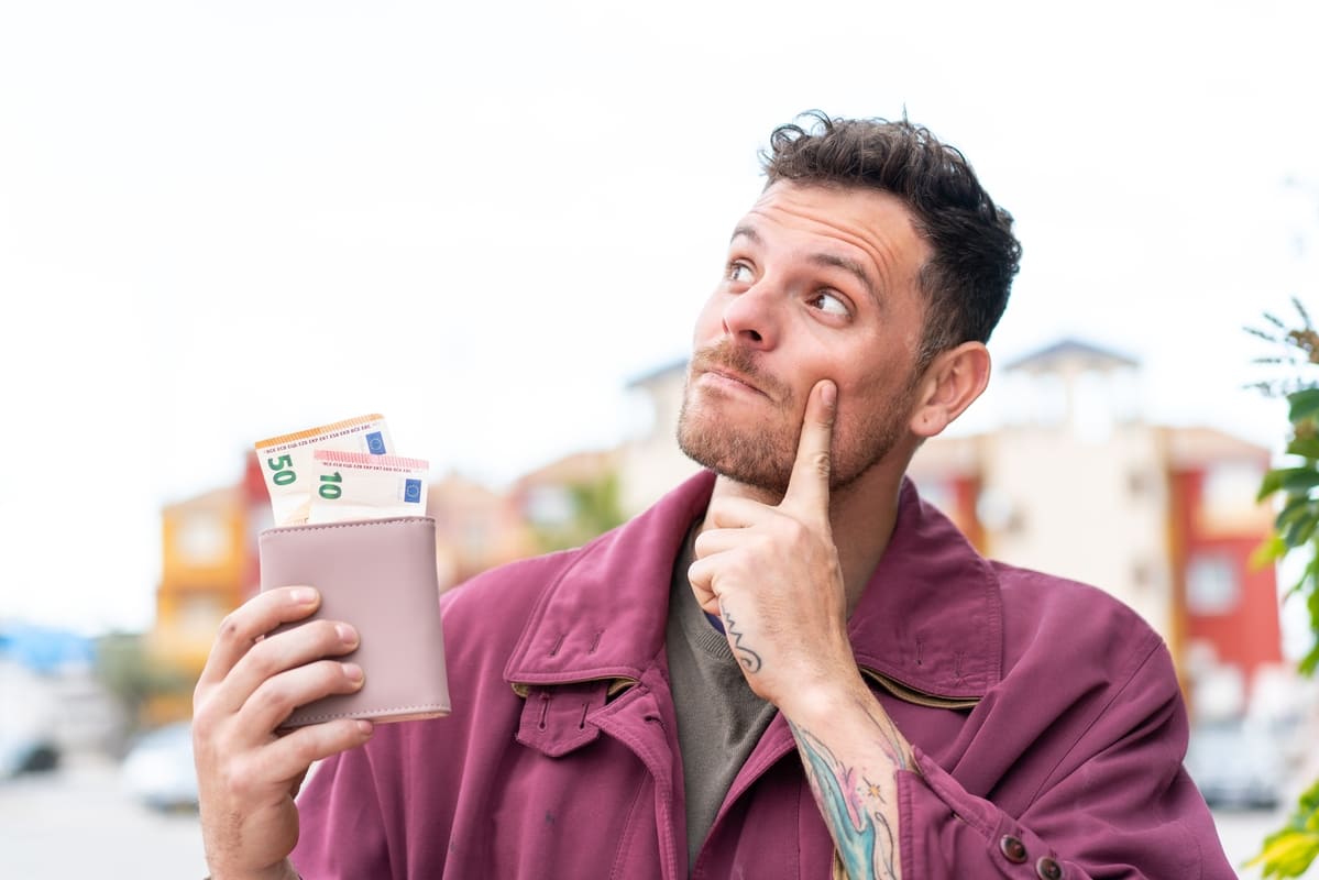 Kaskokindlustuse kontroll - noor mees tahakotiga, kust paistab paar rahatähte