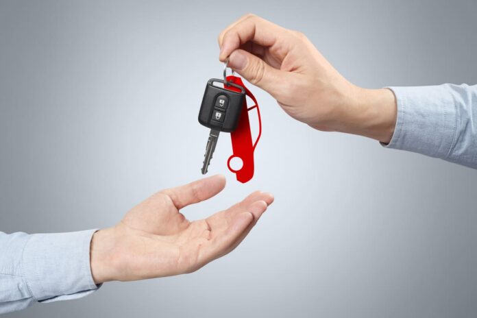 Kaskokindlustuse ümbervormistamine - autovõtmeid koos punase võtmehoidjaga antakse käest kätte
