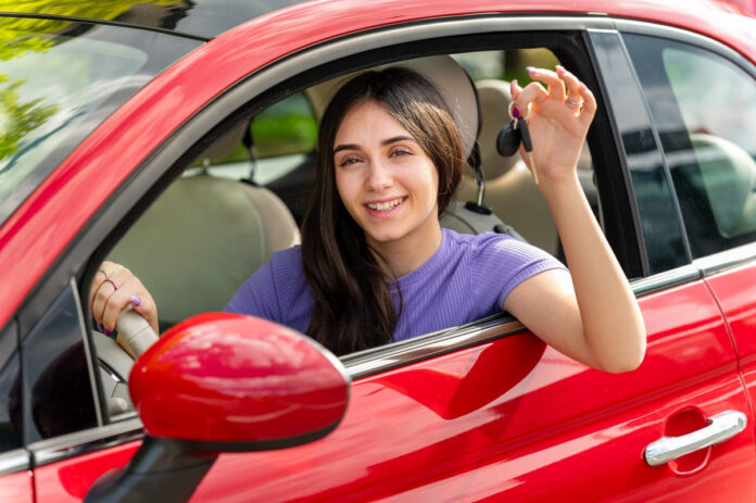 Kaskokindlustuse asendusauto - rõõmus naine punase auto rooli taga