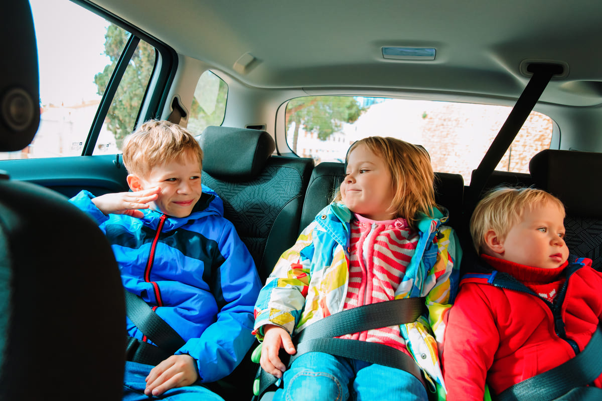 Kaskokindlustuse asendusauto - kolm kirevates jopedes last auto tagaistmel