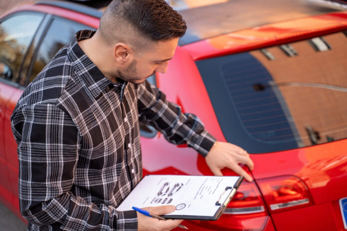 Milleks kaskot vaja on - ruudulises särgis mees punase auto kriimustusi uurimas