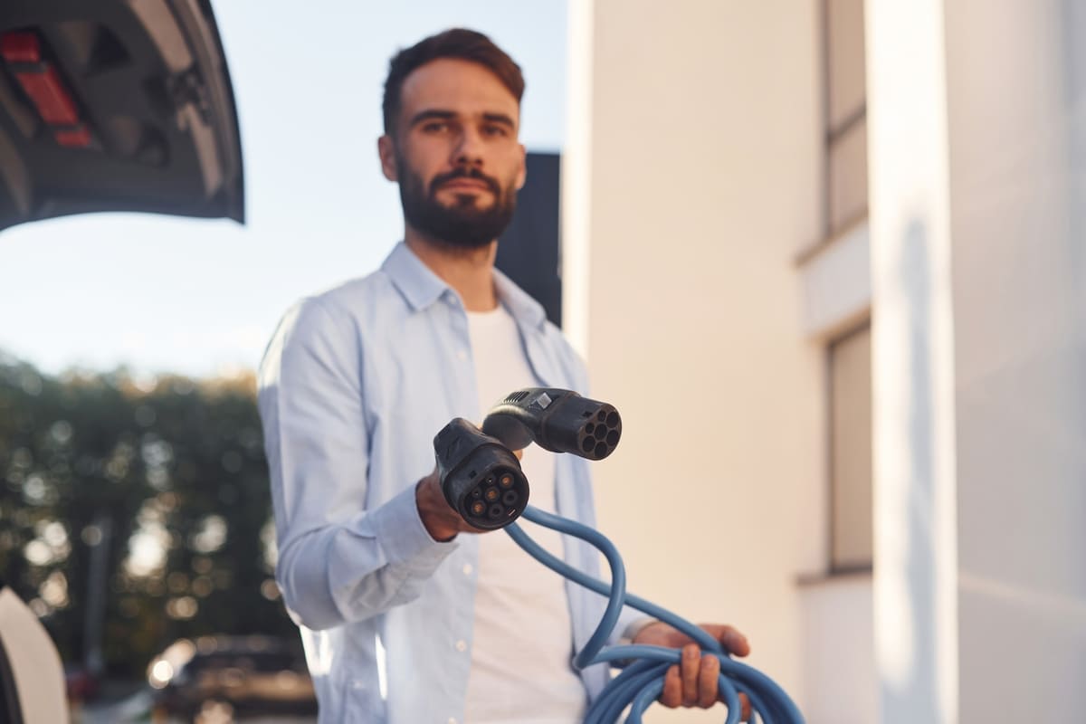 Kasko laadimisjaama kaitse - laadimisjuhe heledates riietes tumedapäise mehe käes