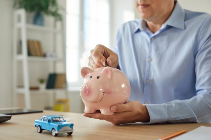 Soodne kaskokindlustus - naine roosasse hoiupõrsasse münte lisamas, kõrval helesinine mudelauto