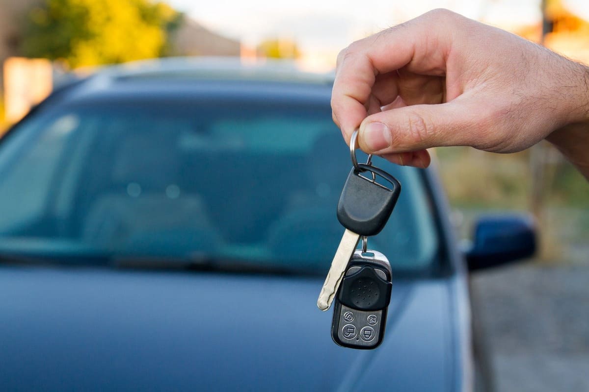 Kaskokindlustuse lisakaitse - autovõtmetega käsi ja taustal tume auto